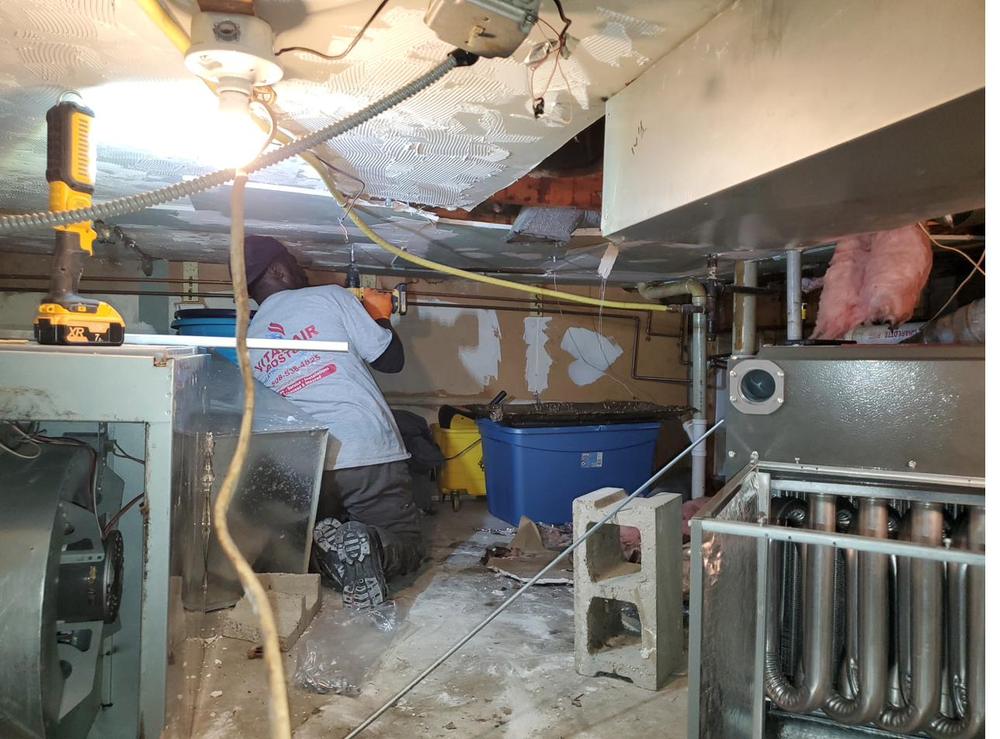 Hans working on a furnace in a basement crawlspace